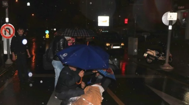 Motosikletten düşen kadını şemsiyelerle yağmurdan korudular